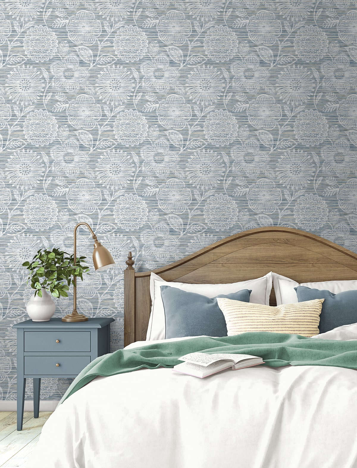 Bedroom with curved wooden headboard, blue nightstand, brass lamp, white bedding, blue pillows, green throw, floral wallpaper.