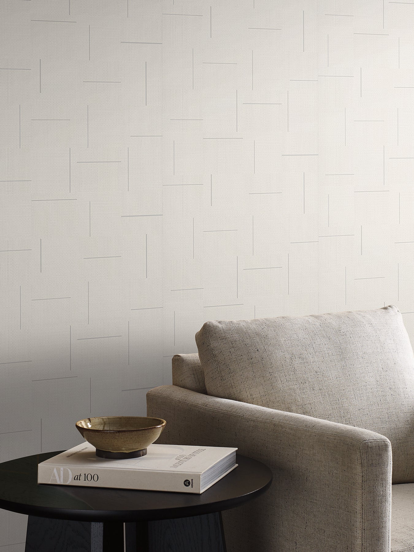 Ivory geometric wallpaper with a subtle block-weave texture on a light wall.
