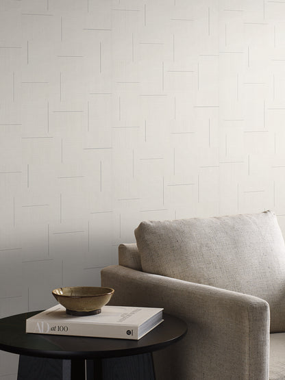 Ivory geometric wallpaper with a subtle block-weave texture on a light wall.