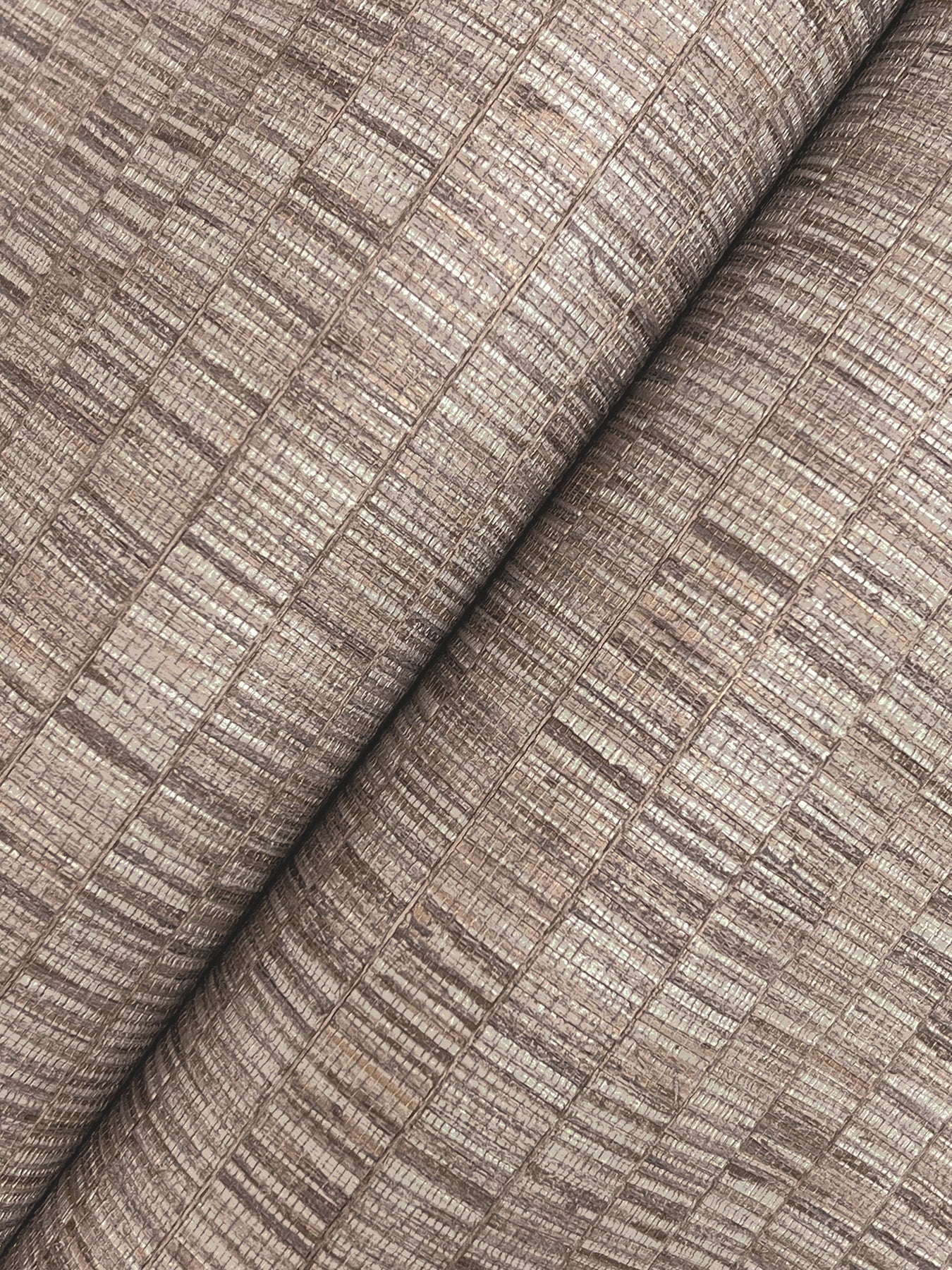 Taupe wallpaper with a grey transitional stripe pattern, rolled.