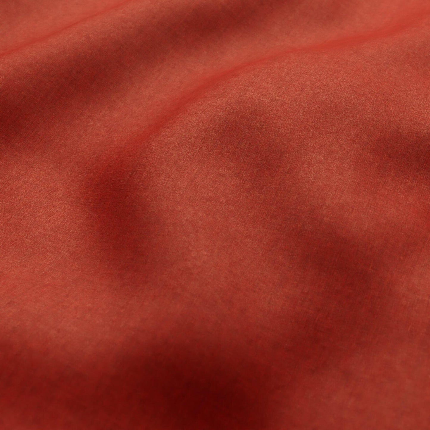 Close-up of coral red velvet fabric with soft folds and smooth texture.