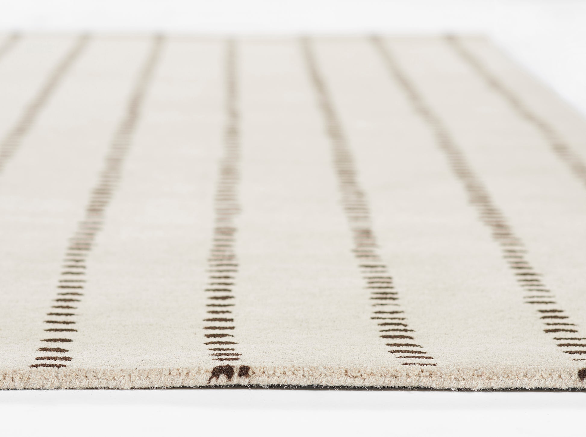 Beige rug with dark brown dashed vertical stripes, low-pile weave and fringe edge.