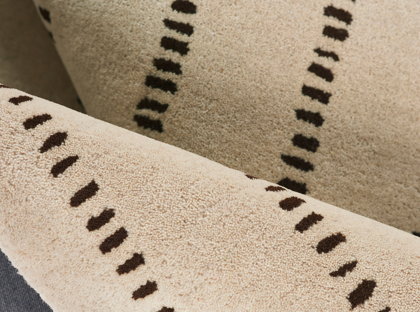 Beige textured rug with dark brown dash pattern; soft tufted pile for modern living spaces.