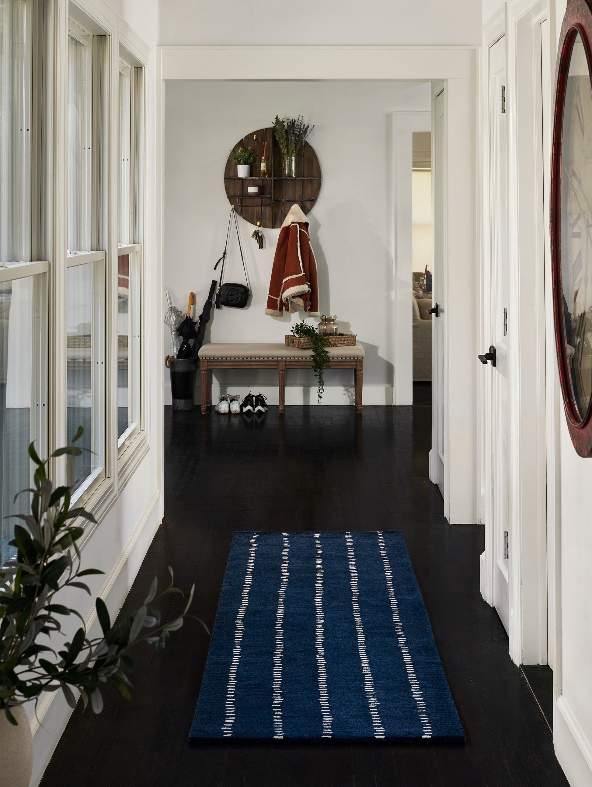 Navy blue rug with a white vertical stripe pattern in a dark hardwood hallway.