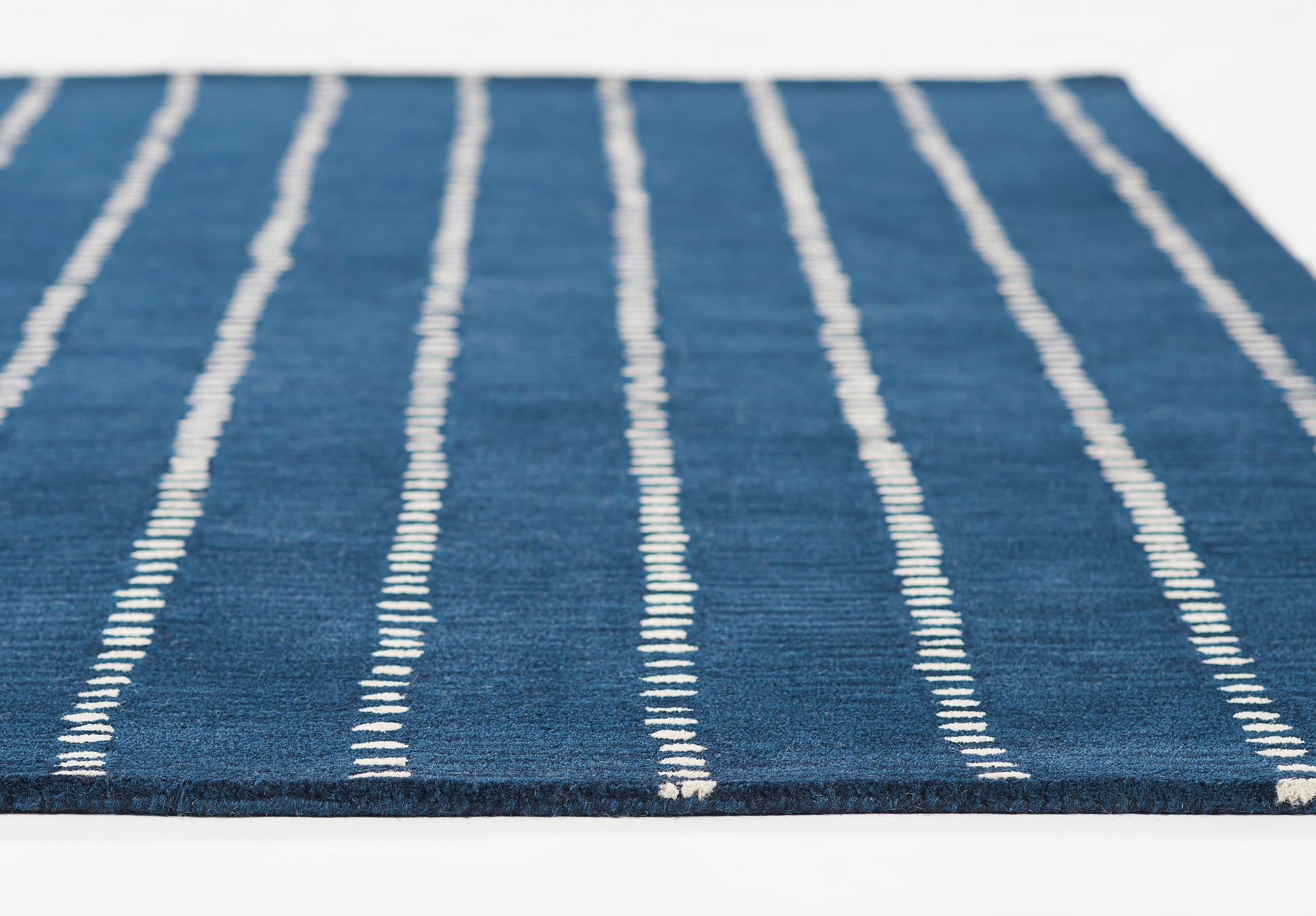 Navy blue flat-weave rug with white vertical stripes for a modern casual look.