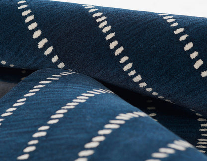 Navy blue rug with white dotted dash stripes, rolled and folded.