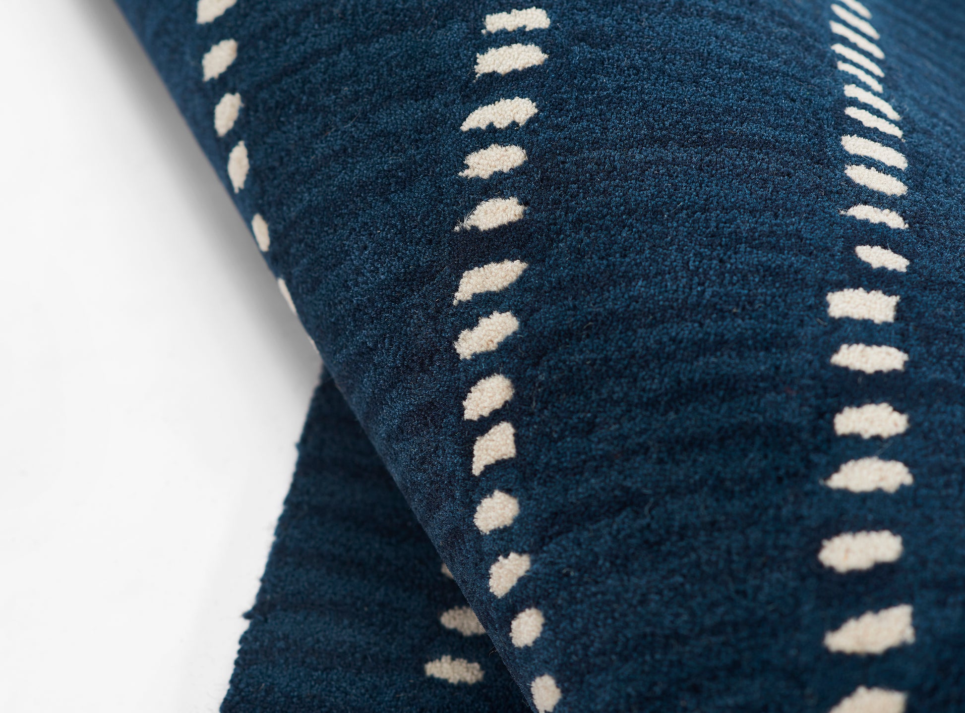Navy blue terry cloth towel with cream dotted vertical stripes.