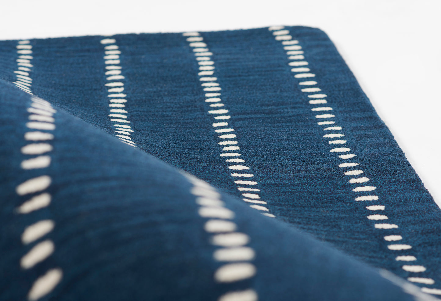 Navy blue rug with white dashed stripes and soft woven texture; 8' x 10'.