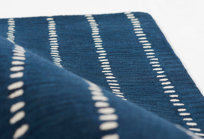 Navy blue rug with white dashed stripes and soft woven texture; 8' x 10'.