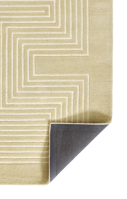 Beige rectangular rug with white geometric stepped-line pattern; folded corner reveals dark underside.