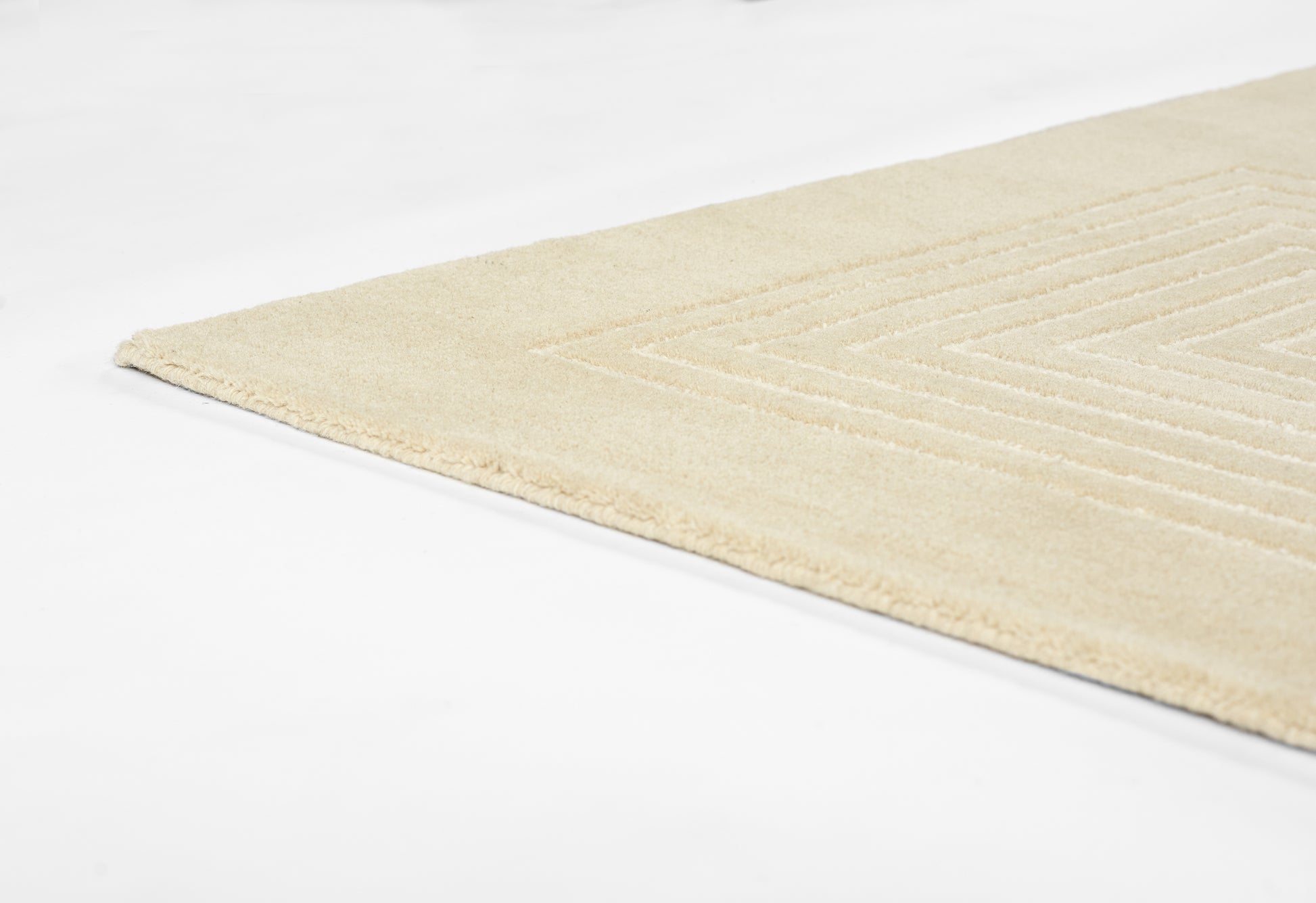 Beige flat-weave rug featuring a subtle geometric rectangular border and soft texture.
