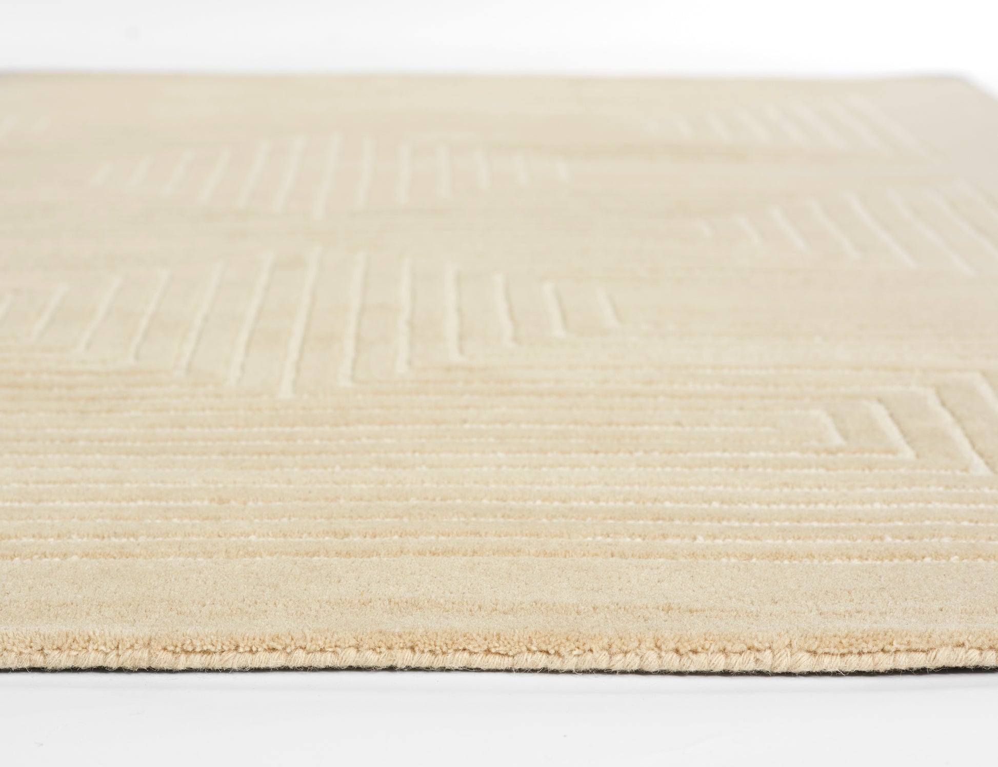 Beige area rug with subtle geometric rectangle pattern and low-pile texture.
