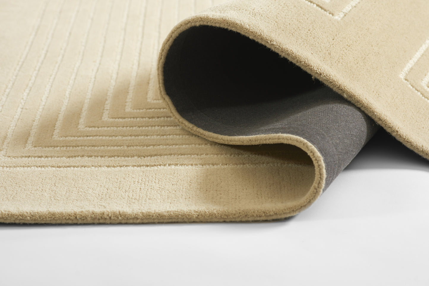 Beige textured runner rug with stitched chevron pattern, rolled at edge showing dark gray underside.