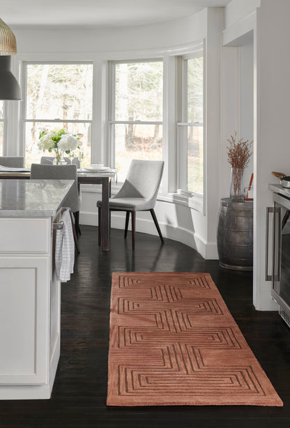 Terracotta geometric flatweave rug in a contemporary white kitchen with dark wood floors and bay-window seating.