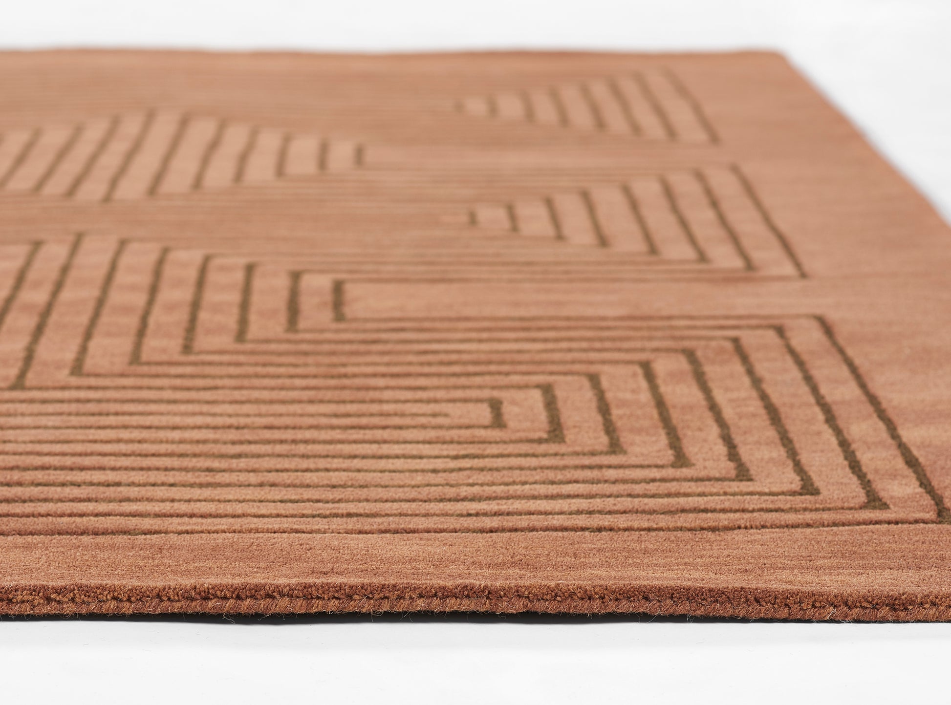 Brown rectangular doormat with a raised geometric stepped-line pattern and textured surface.
