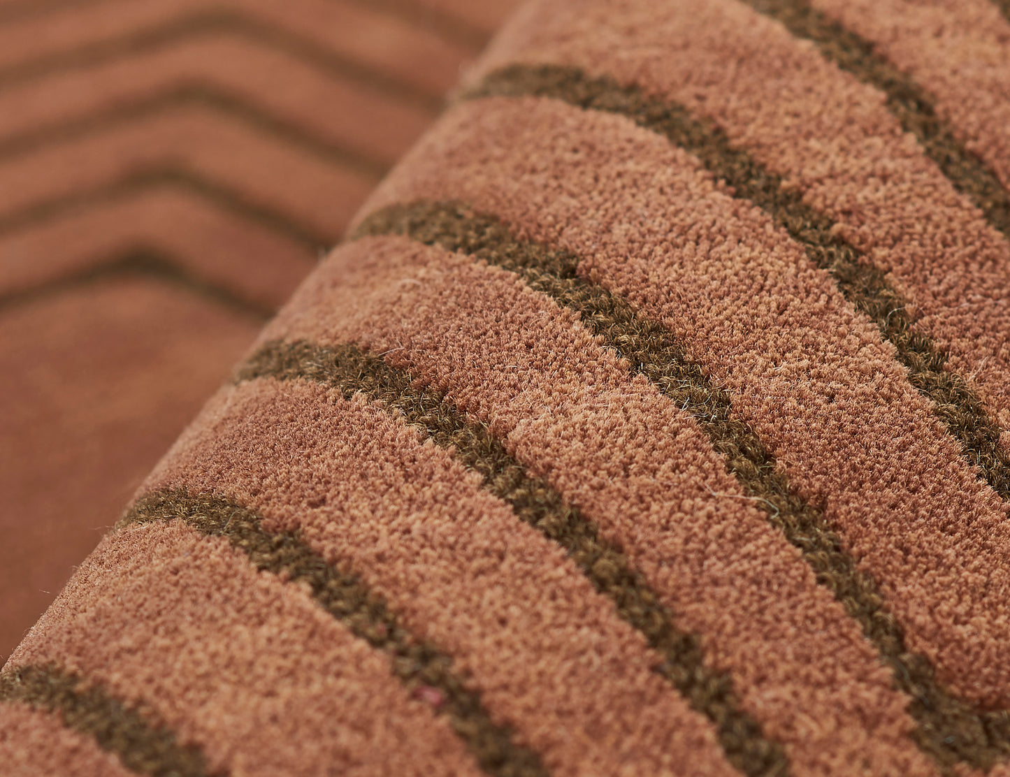 Close-up of pinkish-brown shag rug with dark brown stripes and soft, textured pile.