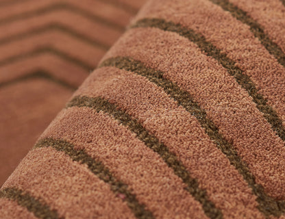 Close-up of pinkish-brown shag rug with dark brown stripes and soft, textured pile.
