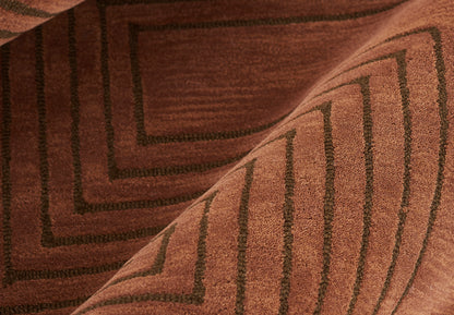 Close-up of a brown woven rug with dark geometric borders and stepped rectangular patterns.