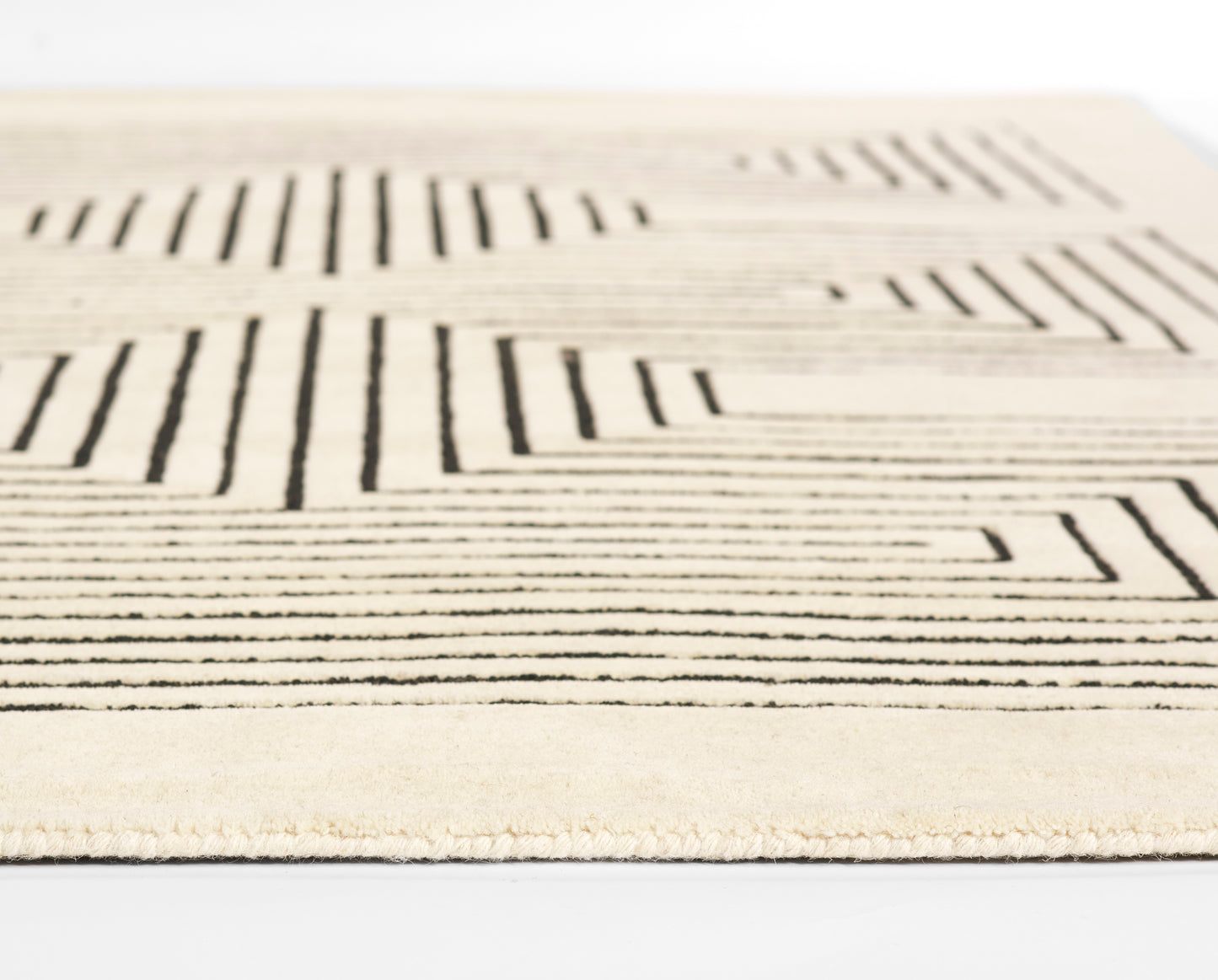 Beige rug with bold black linear geometric pattern; modern, low-pile textile with subtle texture.