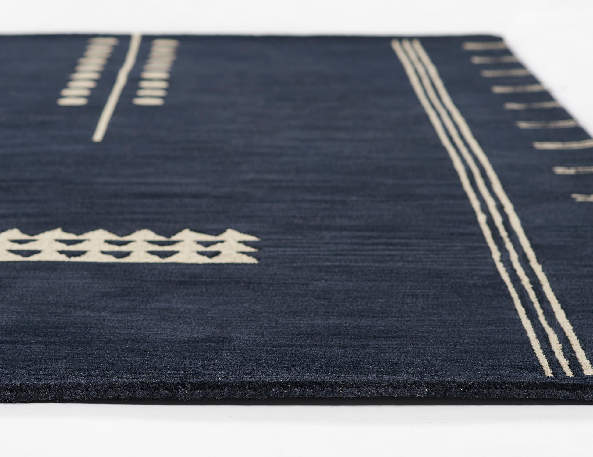 Navy rug with cream geometric patterns: parallel edge lines, cross motifs and stripes
