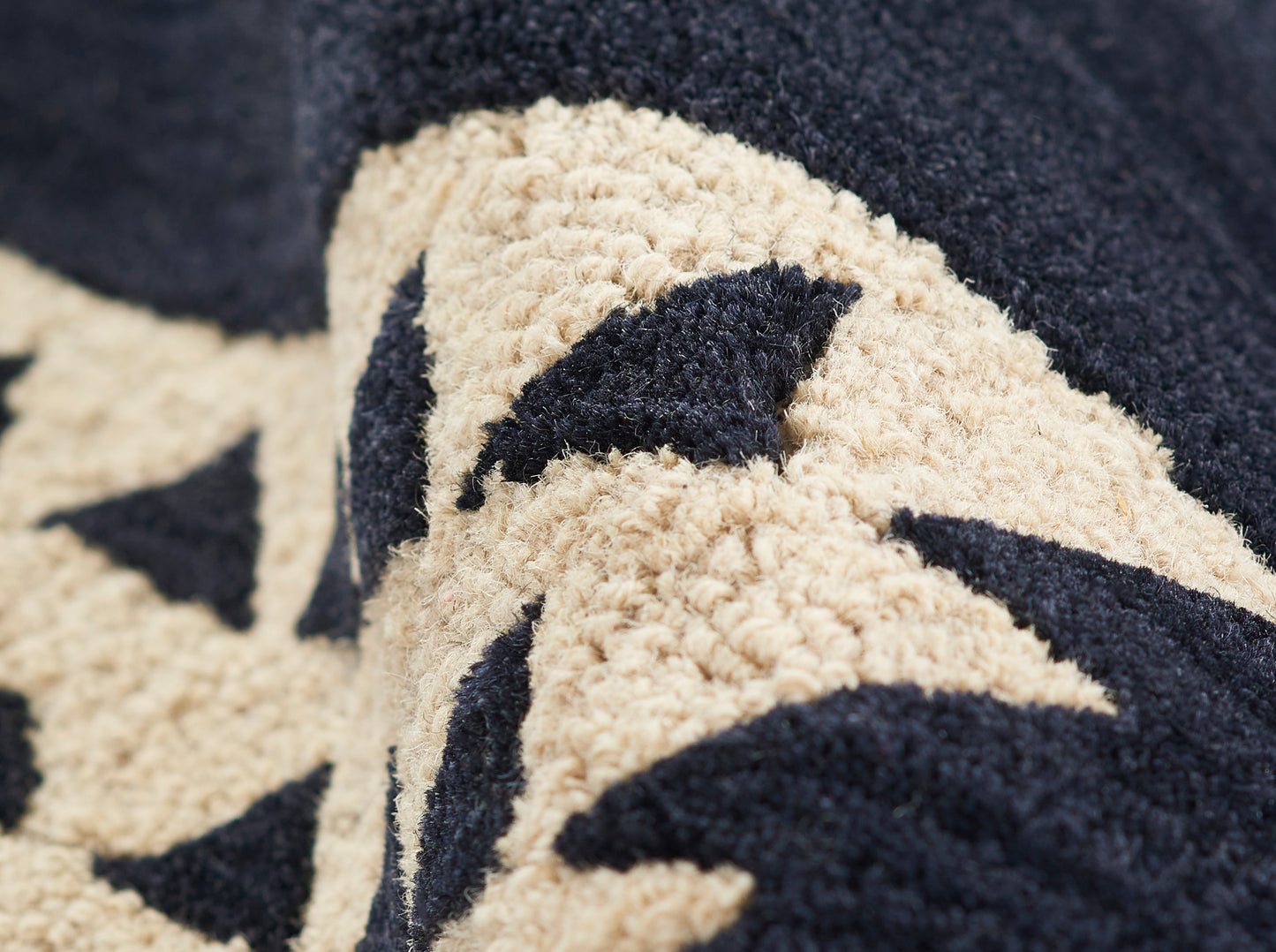 Beige and navy boucle fabric with bold geometric pattern; cozy throw blanket texture for lounge decor.