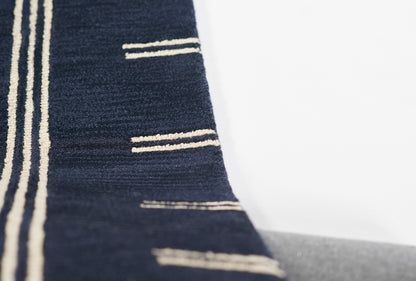 Navy blue woven rug with beige vertical stripes and small horizontal bar accents; modern nautical decor.