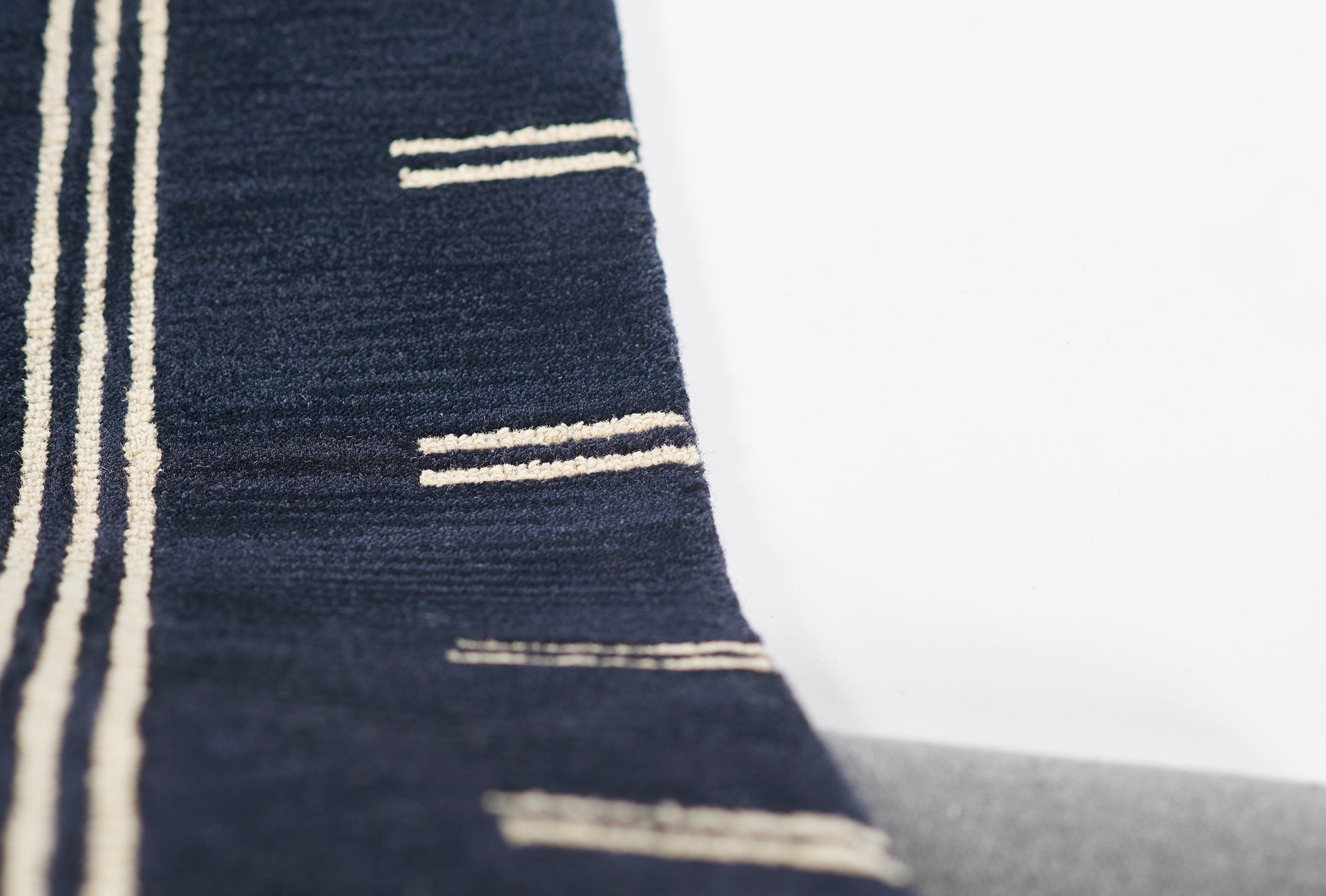 Navy blue woven rug with cream stripes in vertical and short horizontal lines; modern rug.