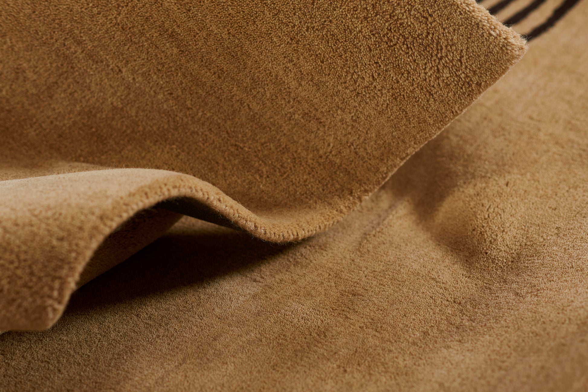 Tan suede fabric close-up with soft folds and textured nap.