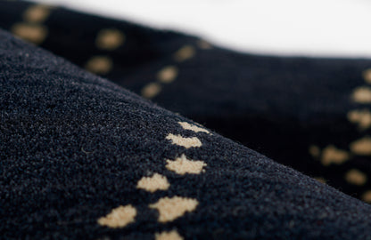 Close-up of dark navy rug with a row of cream diamond motifs; soft woven texture.