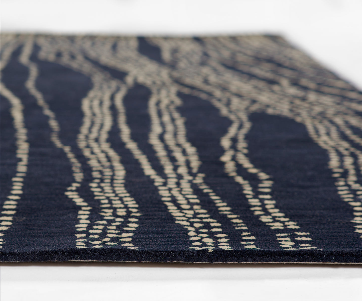 Navy blue flat-weave rug with cream irregular wavy stripes and textured surface.