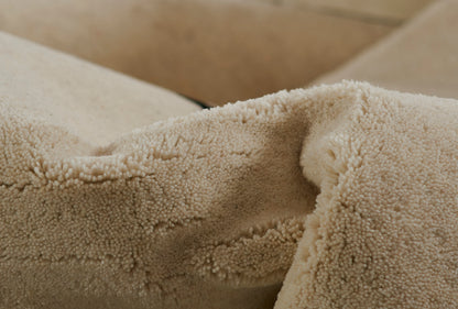 Close-up of creamy beige sherpa rug pile with thick plush texture.