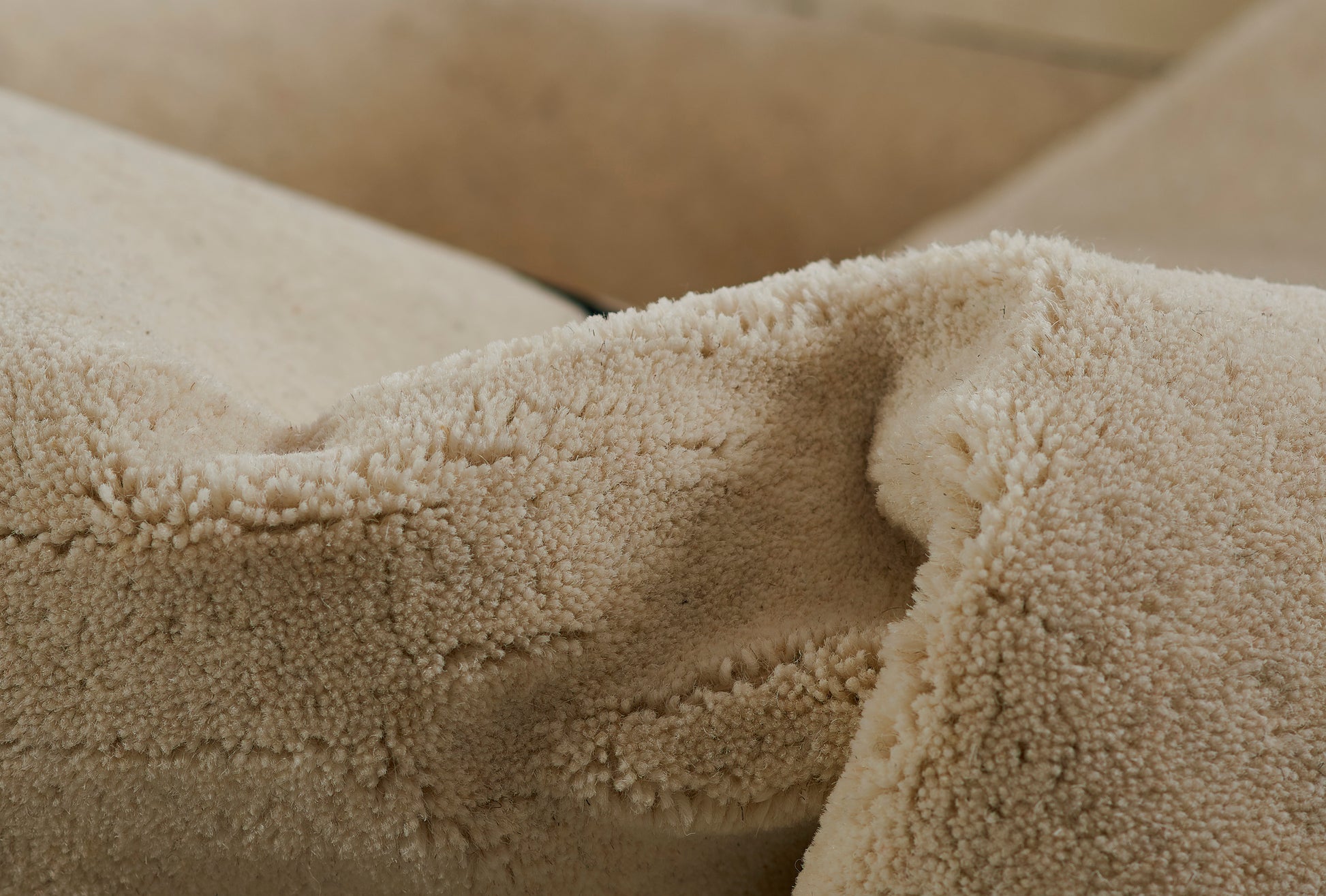 Beige faux-sherpa fleece rug close-up, plush textured pile.
