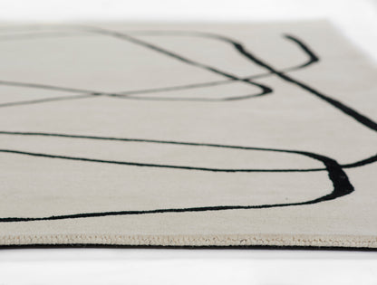 Close-up of a cream rug with bold black abstract curved lines, woven texture, modern minimalist decor.