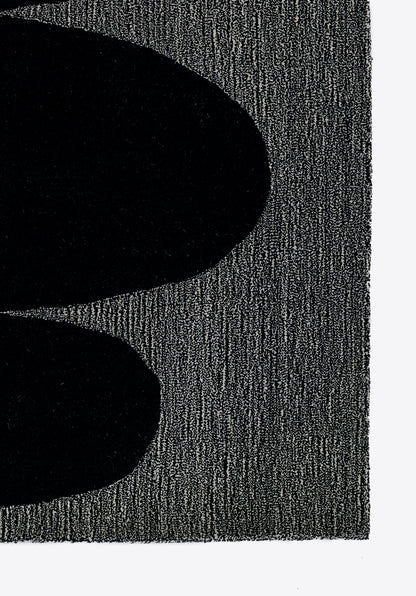 Close-up of two large black oval shapes on a textured gray surface; abstract minimalist design.