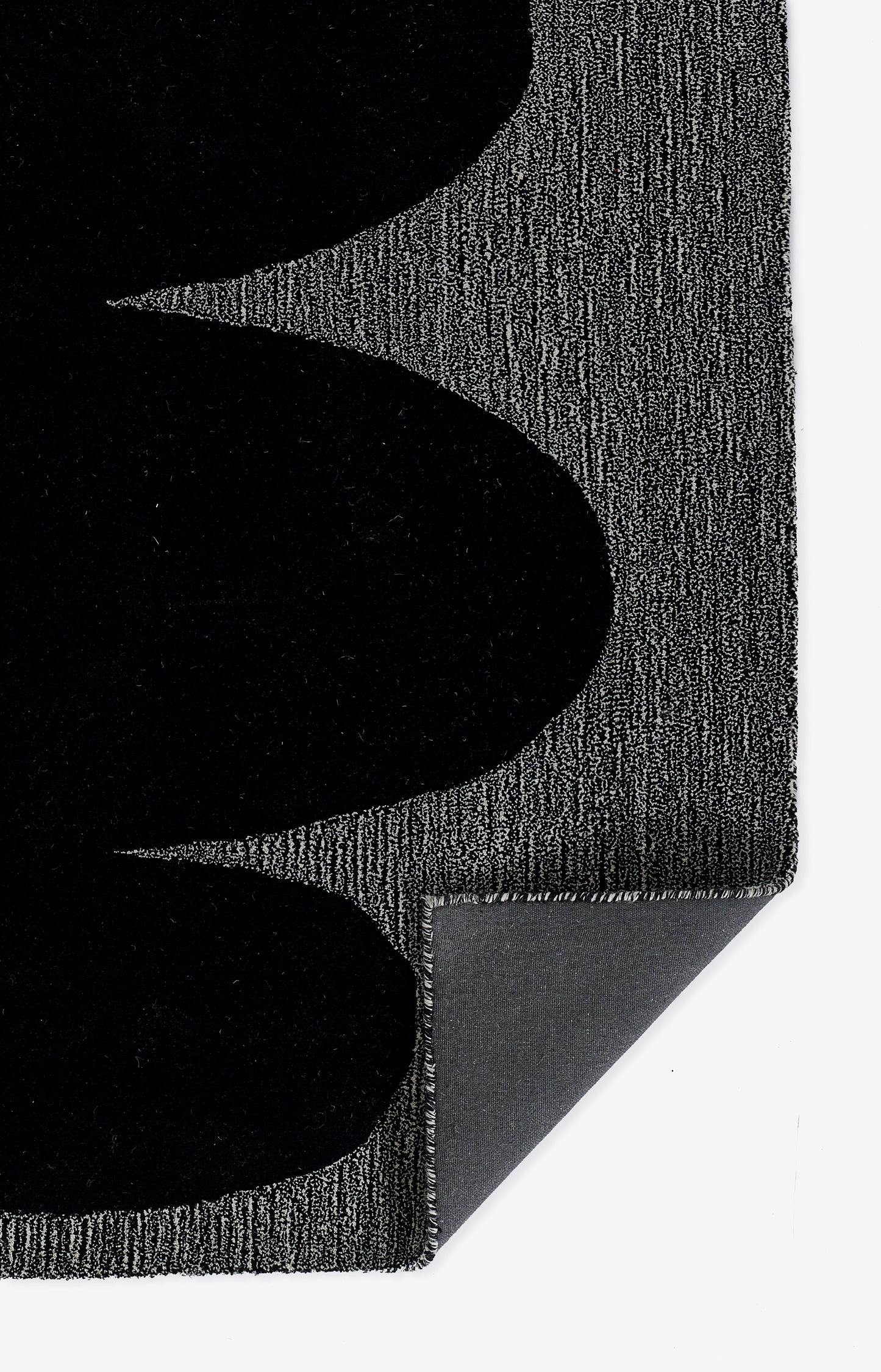 Gray textured rug with bold black curved shapes; modern geometric design, corner folded to reveal the underside.