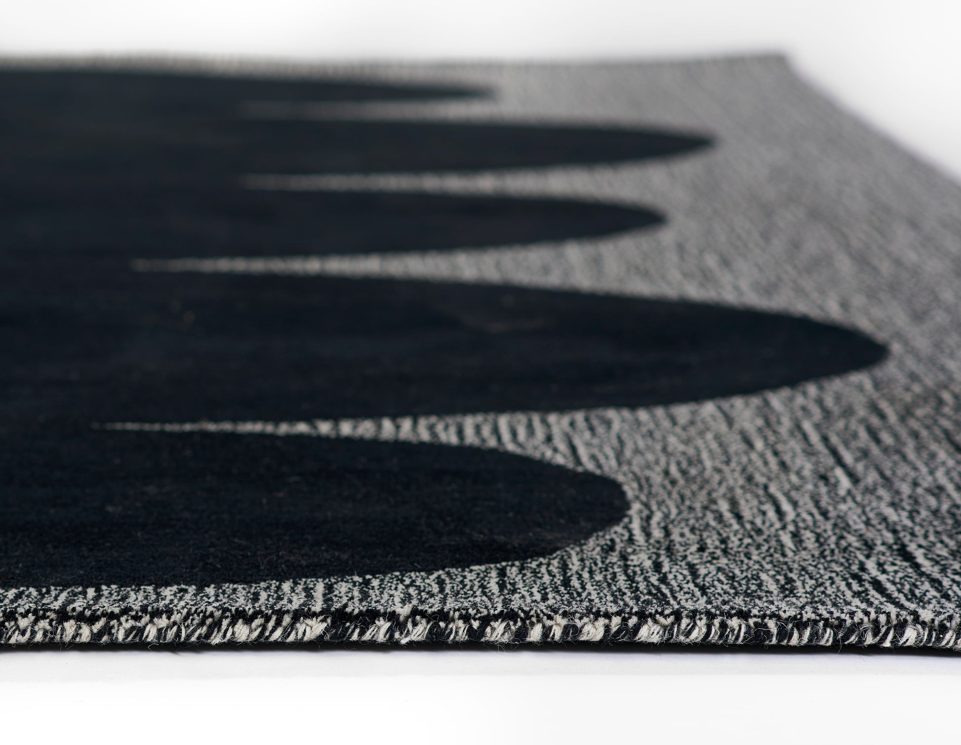 Gray textured runner rug with bold black oval pattern along the edge; looped pile, modern geometric style; 2'6" x 8'.