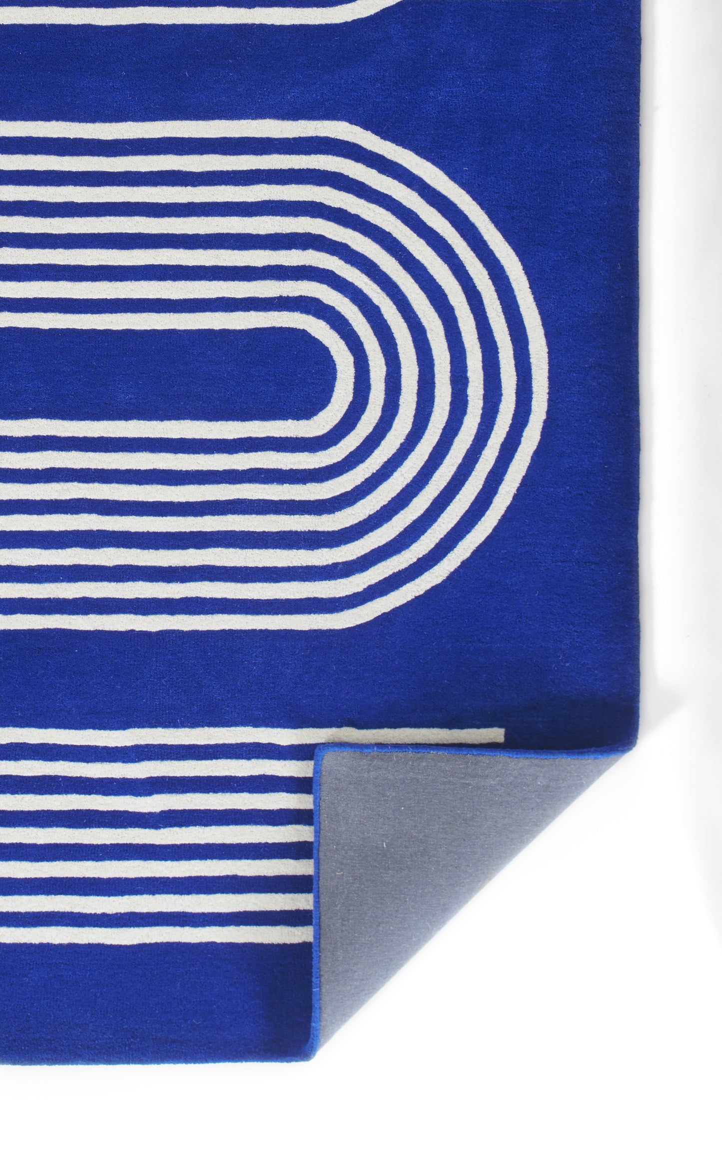 Blue abstract rug with white concentric curved lines and a gray folded corner accent, 5' x 8'.