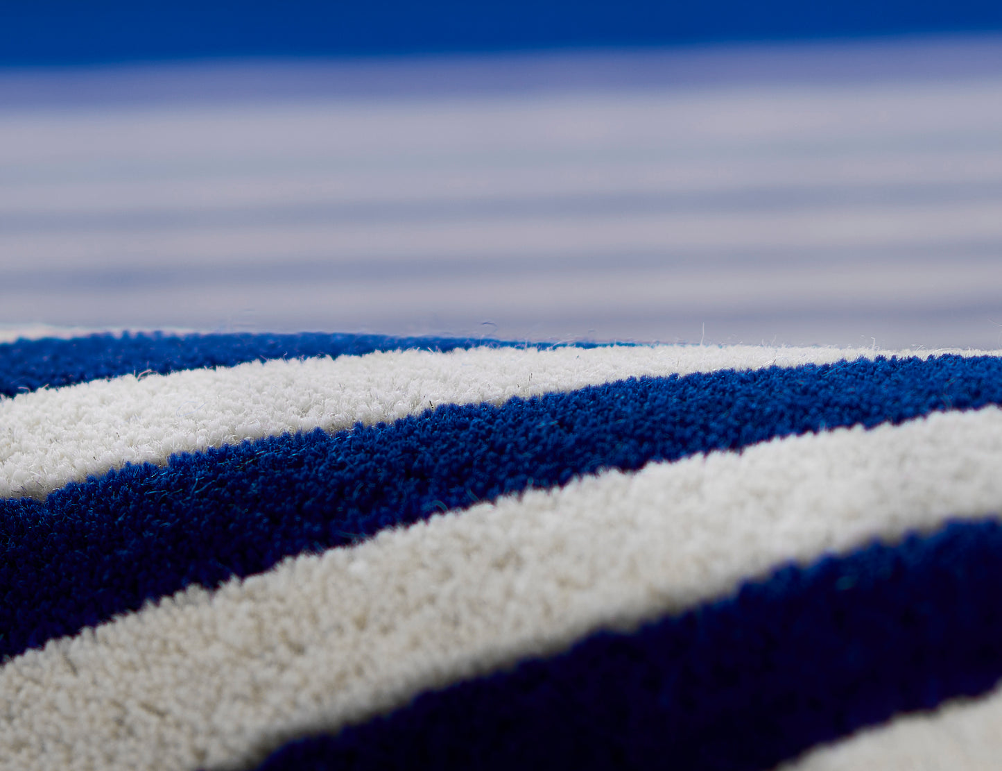 Close-up of plush blue and white striped rug fibers with thick texture.