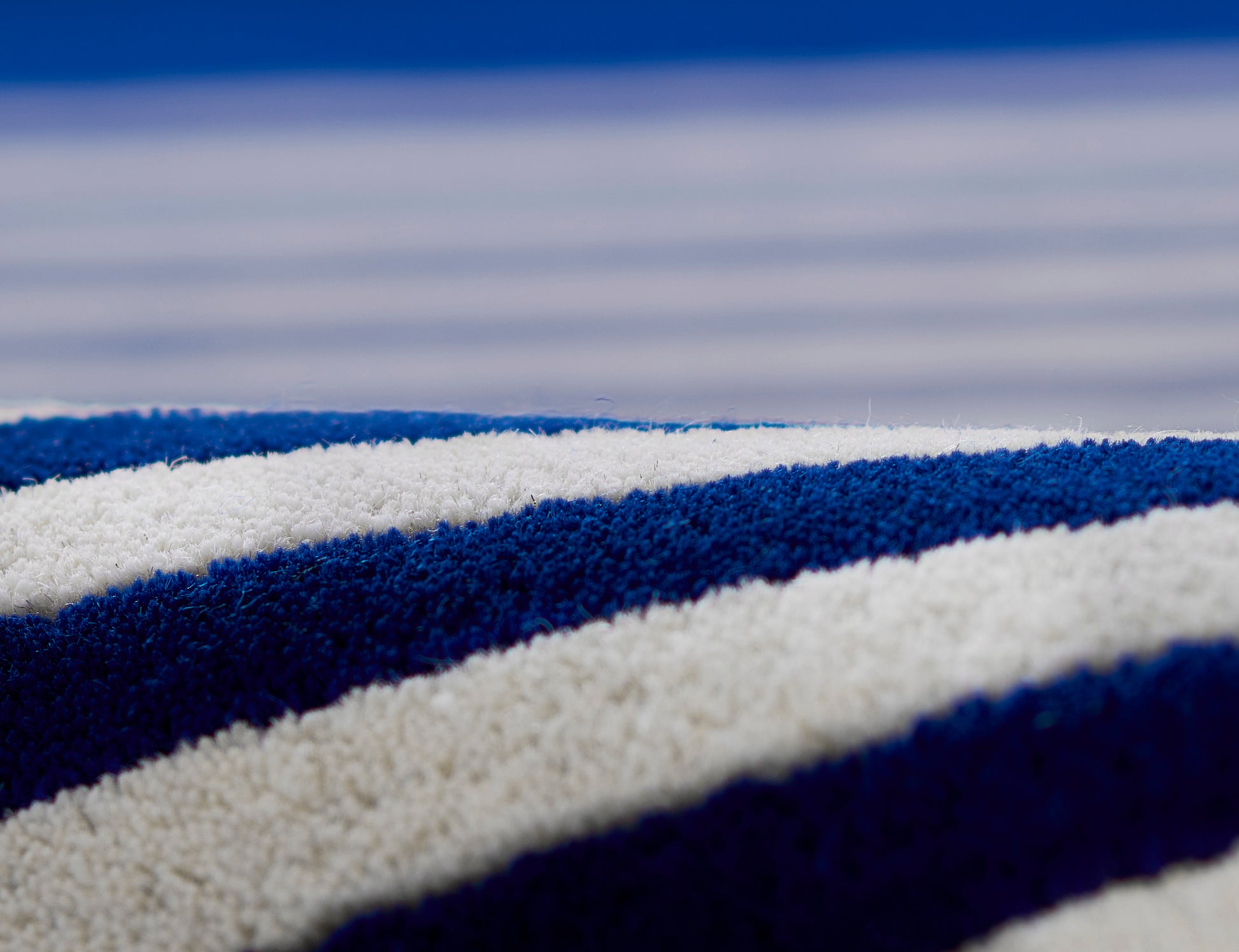 Close-up of a plush blue and white striped rug with soft looped fabric.