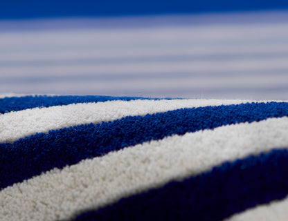 Close-up of a plush rug with blue & white stripes, soft pile, modern coastal decor.