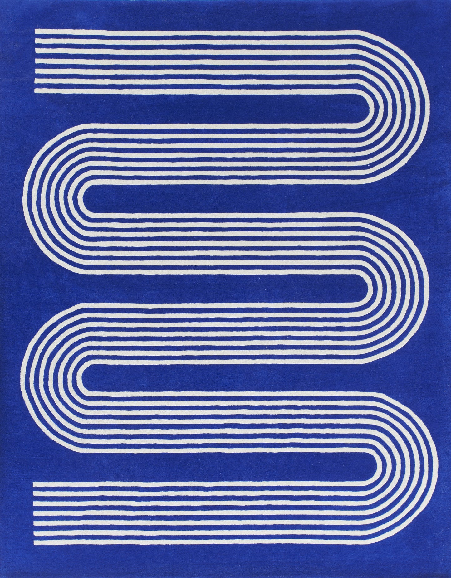 Blue textile with white parallel curved stripes forming an elongated S; modern geometric rug or wall art.
