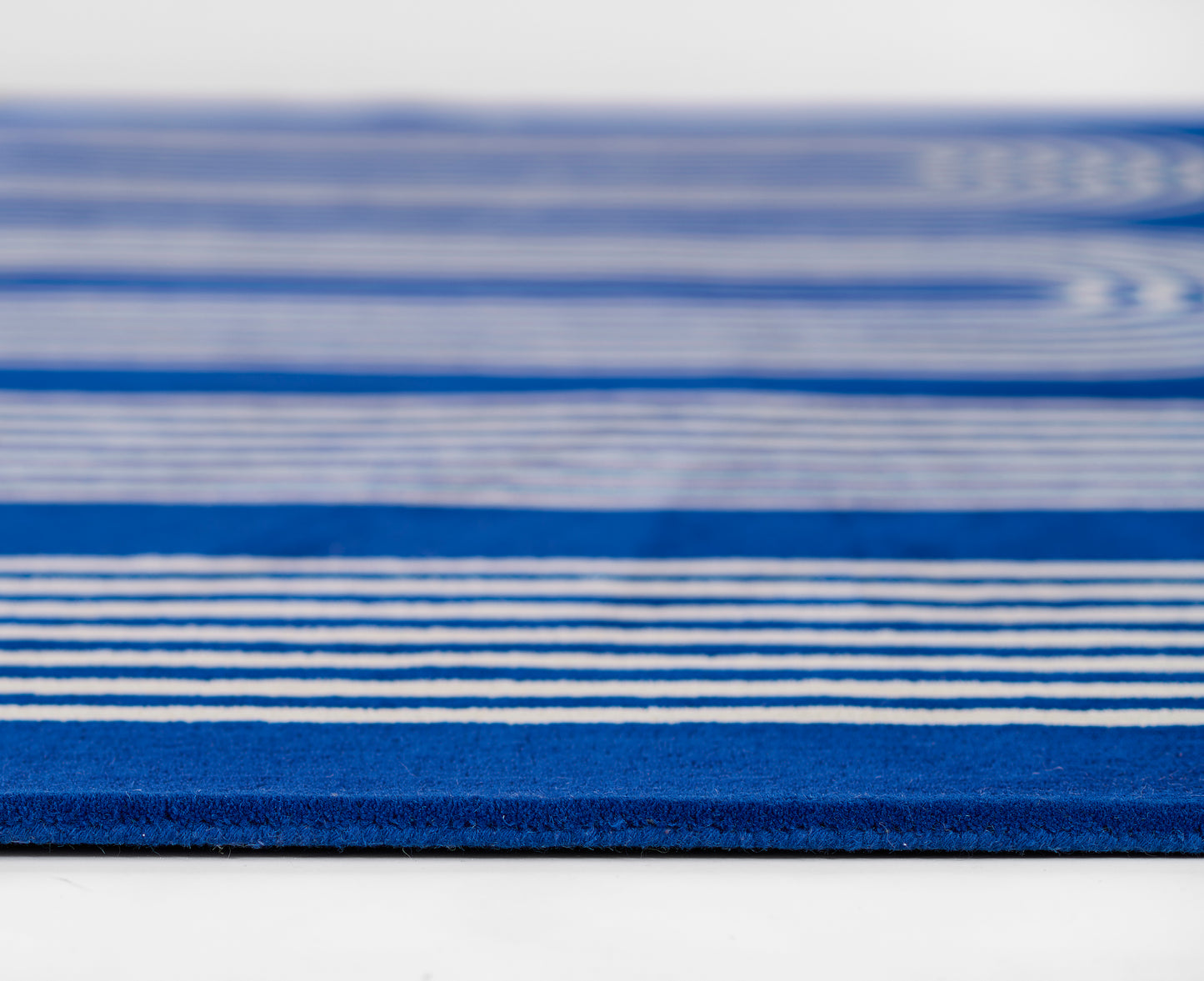 Blue striped rug with white lines, thick woven texture, coastal floor decor.