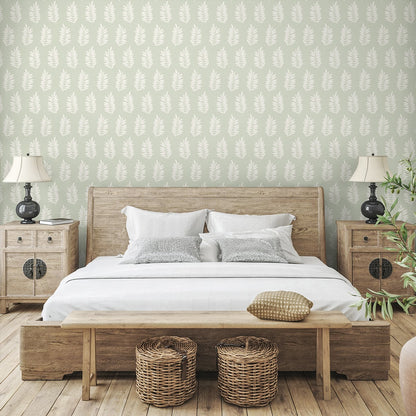 Rustic wooden bed with white bedding, two nightstands, bench at foot, wicker baskets, leafy wallpaper and lamps.
