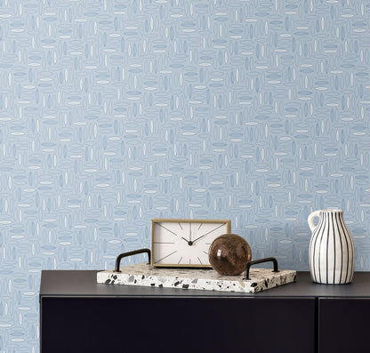 Blue geometric wallpaper behind a dark cabinet, with a speckled marble tray holding a square clock, brown orb, and striped ceramic pitcher.