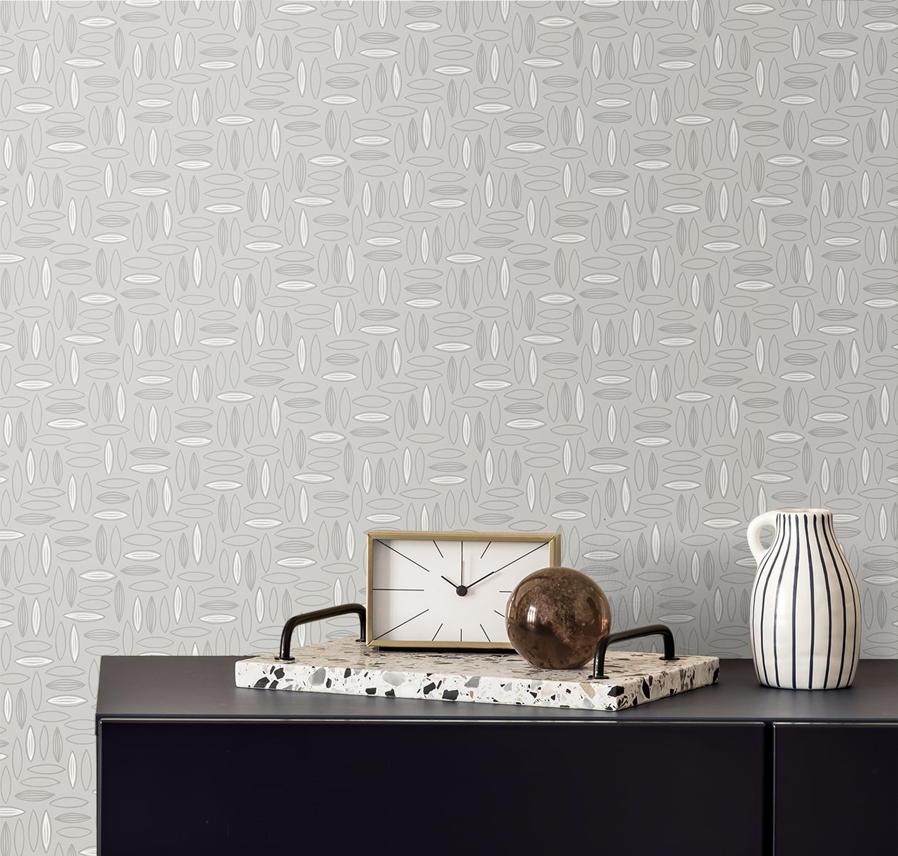 Grey patterned wallpaper, dark console with marble tray, wooden-framed clock, brown orb, and striped pitcher.
