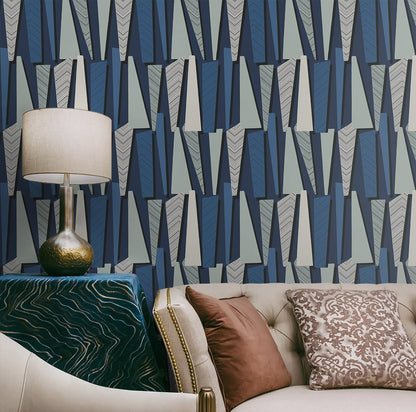 Geometric navy & gray wallpaper; beige tufted sofa, brown damask cushions; brass lamp, cream shade, green velvet table.