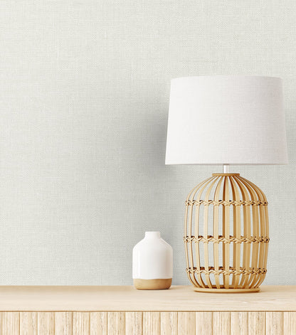 Soft off-white linen fabric swatch on a light wood surface, close-up showing the texture.
