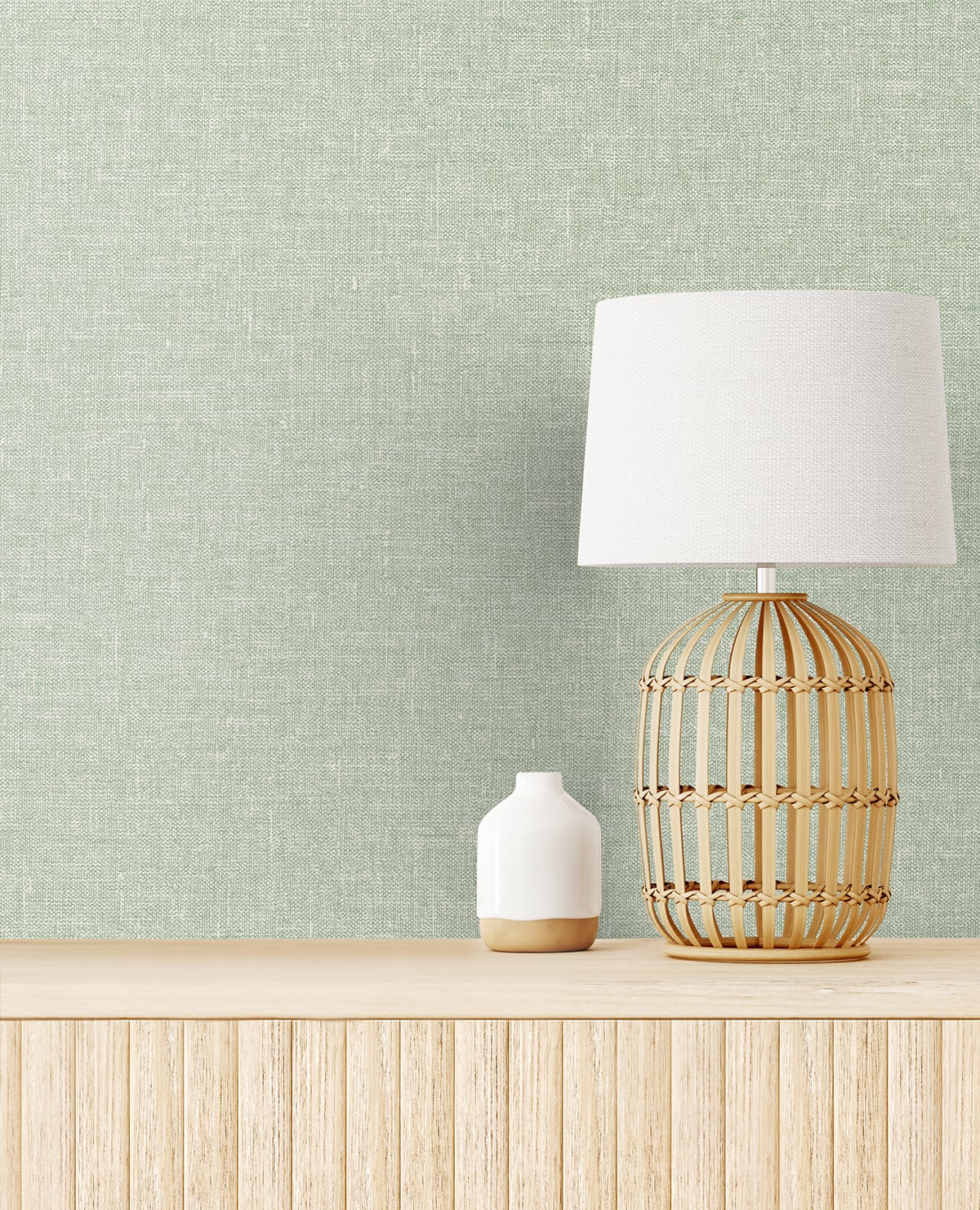 Rattan lattice table lamp with white shade and a small white ceramic vase on a light wood sideboard.