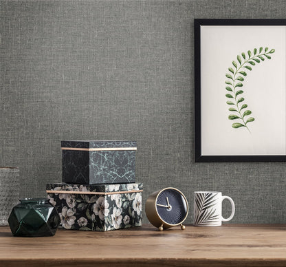 Wooden tabletop with floral and marble boxes, green faceted vase, blue-and-gold clock, striped mug, framed fern print on gray wall.