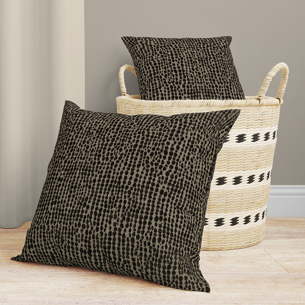 Chocolate solid fabric throw pillows; one propped in a woven basket, another on a light wood floor.
